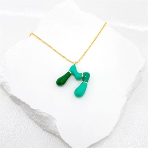 Detailed view of bubble initial pendant with green enamel on a golden necklace