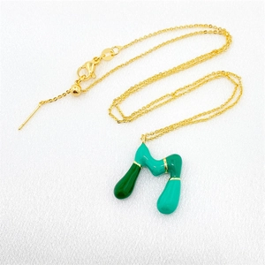 Detailed close-up of a gold-plated necklace with a green enamel abstract bubble pendant