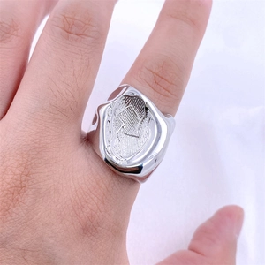 Gros plan d'une bague argentée à texture irrégulière et design lave rétro portée