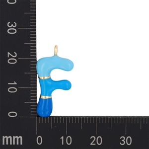 Macro view of blue enamel bubble letter F pendant showing dimensions on a scale ruler