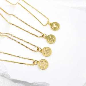 Detailed macro view of four golden zodiac pendants with hollow signs on silk background