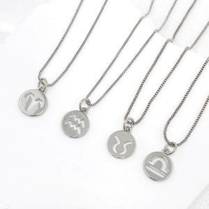 Detail of four silver zodiac coin necklaces featuring Aries, Aquarius, Taurus, and Libra