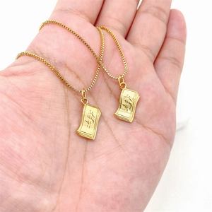Detailaufnahme von zwei goldenen Dollar-Anhängern an Box-Ketten in der Hand gehalten
