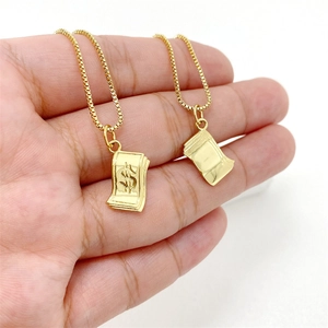 Nahaufnahme eines goldenen Dollarzeichen-Anhängers an einer Kette in der Hand