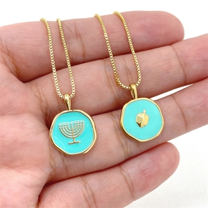 Détail des pendentifs Hanouka Menorah et Dreidel en émail bleu sur la main d'un modèle