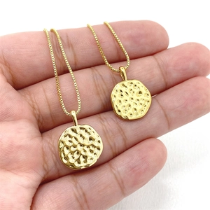 Gros plan de deux pendentifs ronds dorés avec texture martelée et fines chaînes box