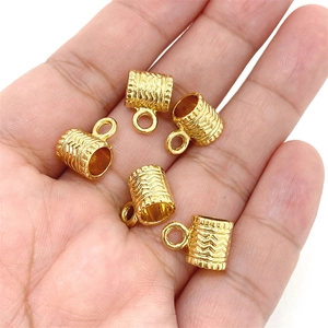 Détails macro de breloques cylindriques en plaqué or avec motifs ondulés en V pour bijoux