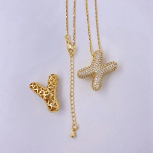 Detail of gold balloon letters X and Y pendants with zircon inlay and box chain