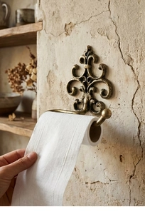 Close-up of vintage cast iron toilet paper holder with ornate fleur-de-lis carving