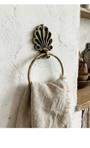 Detail of vintage bronze seashell towel ring with antique finish on a rustic wall
