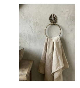Detail of vintage cast iron towel ring with shell relief on a rustic concrete wall