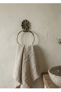 Detailed view of vintage gold seashell towel ring on a textured micro-cement wall