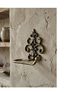 Detail of vintage fleur-de-lis wall-mounted cast iron tissue holder with bronze finish