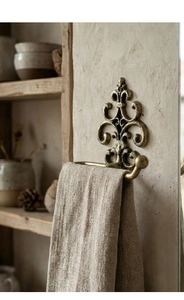 Detail of vintage bronze cast iron towel rack with baroque patterns on textured wall