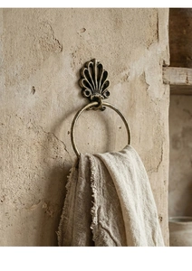 Detail of vintage bronze shell-shaped towel ring on rustic textured wall