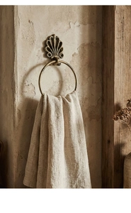 Detail of vintage bronze seashell towel ring on textured wall with rustic wooden decor