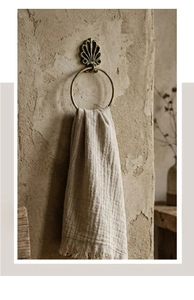 Detail view of vintage shell embossed brass towel ring with rustic textured wall backdrop