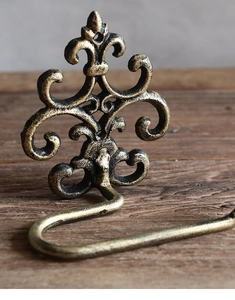 Detail of vintage cast iron towel hook with fleur-de-lis pattern and gold finish