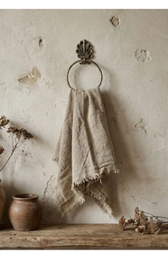 Detail of vintage bronze towel ring with shell relief on a rustic textured wall