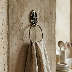 Vintage bronze towel ring with seashell base and linen towel on a textured rustic wall