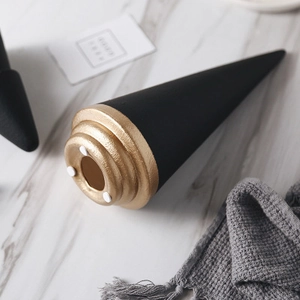 Modern black ceramic Christmas tree decor with textured gold base on marble surface