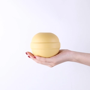 Vaso in ceramica opaca giallo zenzero tenuto in mano con design a coste per arredo nordico