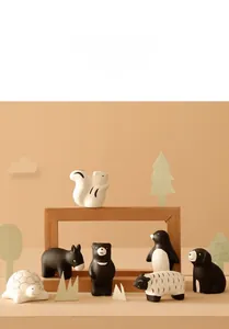 Detail of minimalist ceramic animal figurines including penguin and bear on a wooden shelf