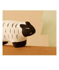 Macro shot of a cute ceramic sheep figurine on a wooden stand with a warm orange backdrop