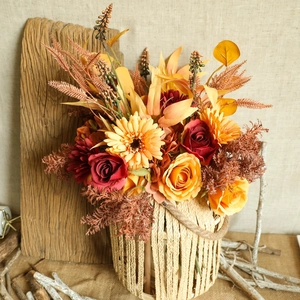 Autumn-themed artificial flower bouquet in a woven basket with warm orange roses and gerberas
