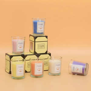 Set bunter Duftkerzen im Glas mit minimalistischen Geschenkboxen auf orangefarbigen auf Orange