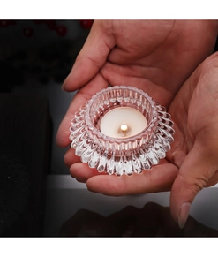 Close-up of a ribbed glass candle holder with a lit white tea light candle inside