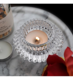 Macro shot of a lotus petal textured glass candle holder with a lit tealight on marble