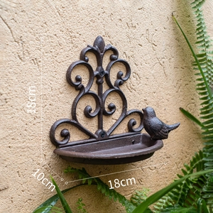 Detail of vintage cast iron bird feeder wall bracket showing 18cm width and rustic texture