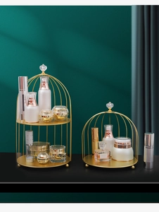 Detailsicht des goldenen Kosmetikregals in Vogelkäfigform mit zwei Ebenen für Parfüms