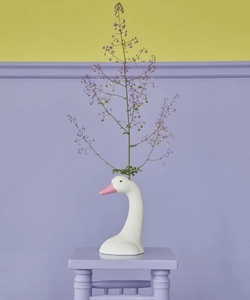 Details einer weißen Schwanenvase aus Keramik mit rosa Schnabel auf einem Hocker