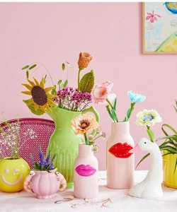 Detail von verspielten Keramikvasen mit Schwanen- und Lippendesign auf rosa Hintergrund