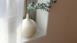 Detail of minimalist ceramic vase with textured horizontal lines near a window