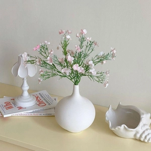 Detail of white ceramic vase with spiral texture and elegant pink flower arrangement