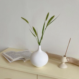 Detail of white ceramic vase with horizontal ribbed texture and minimalist sphere shape