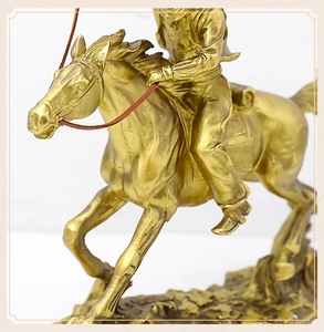 Detailed close-up of a golden cowboy on horseback resin sculpture with metallic finish