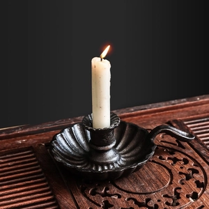 Vintage black cast iron candle holder with ergonomic handle and scalloped base