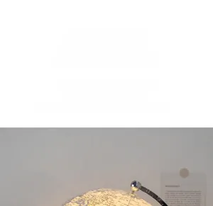 Detailed view of glowing transparent acrylic globe with warm LED lighting and silver stand