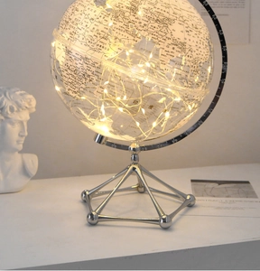 Detail shot of a transparent globe with warm LED copper lights on a silver tripod stand