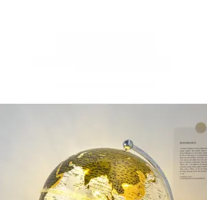 Detail of glowing crystal globe with golden map on a sleek silver metal stand