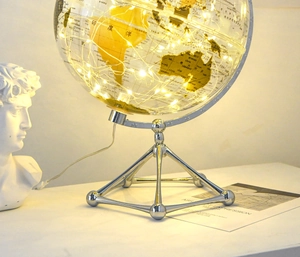 Detail of transparent glowing globe with warm LED lights and silver tripod metal stand