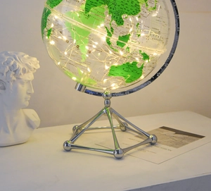 Detailed view of glowing glass globe with LED fairy lights on a silver metal stand