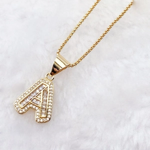 Luxury gold letter A pendant necklace with sparkling cubic zirconia on white fur background