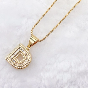 Macro shot of gold plated letter D pendant with sparkling cubic zirconia on plush background