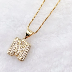 Luxury gold-plated letter M pendant necklace with sparkling cubic zirconia on white fur