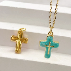 Macro detail of gold cross pendant with turquoise enamel inlay on white steps